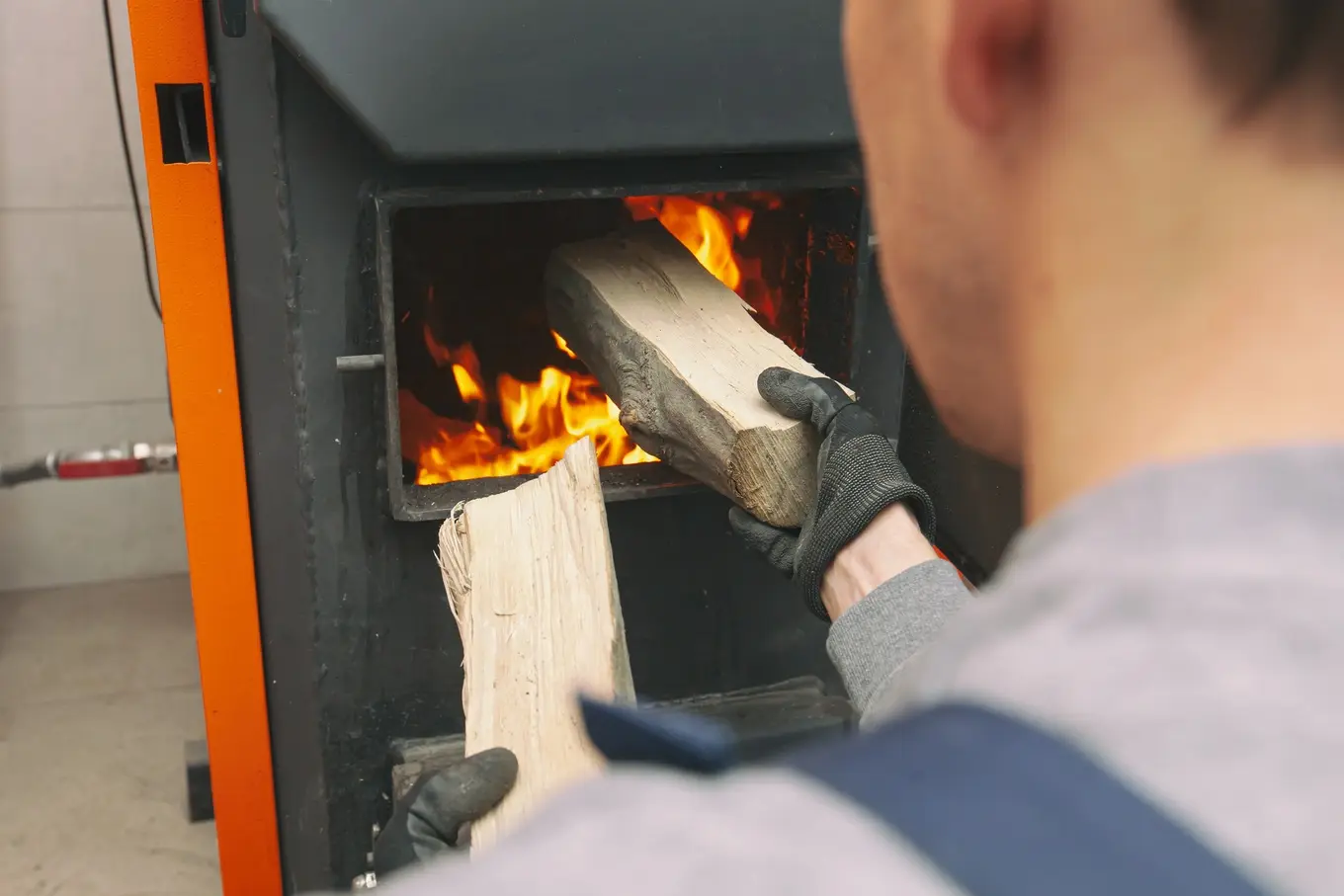mężczyzna wkładający drewno do kotła